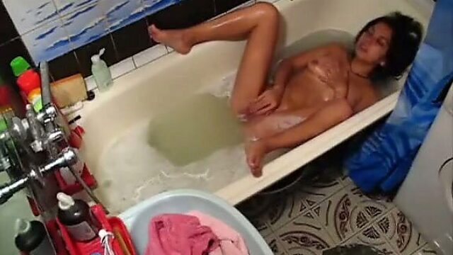 Tanned chick gets into the bathtub and starts masturbating