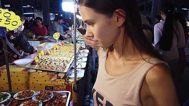 Милая тинка пробует на вкус жуков и тараканов на местном китайском рынке